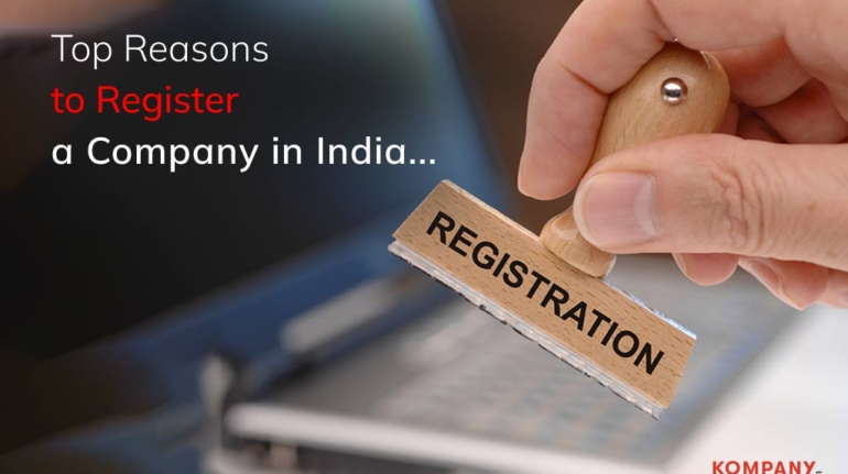 A close-up image of a hand holding a wooden stamp that reads "REGISTRATION" in front of a blurred laptop. The text on the image reads, "Top Reasons to Register a Company in India..." The company's logo, "KOMPANY SERVICES," is displayed in the bottom right corner.