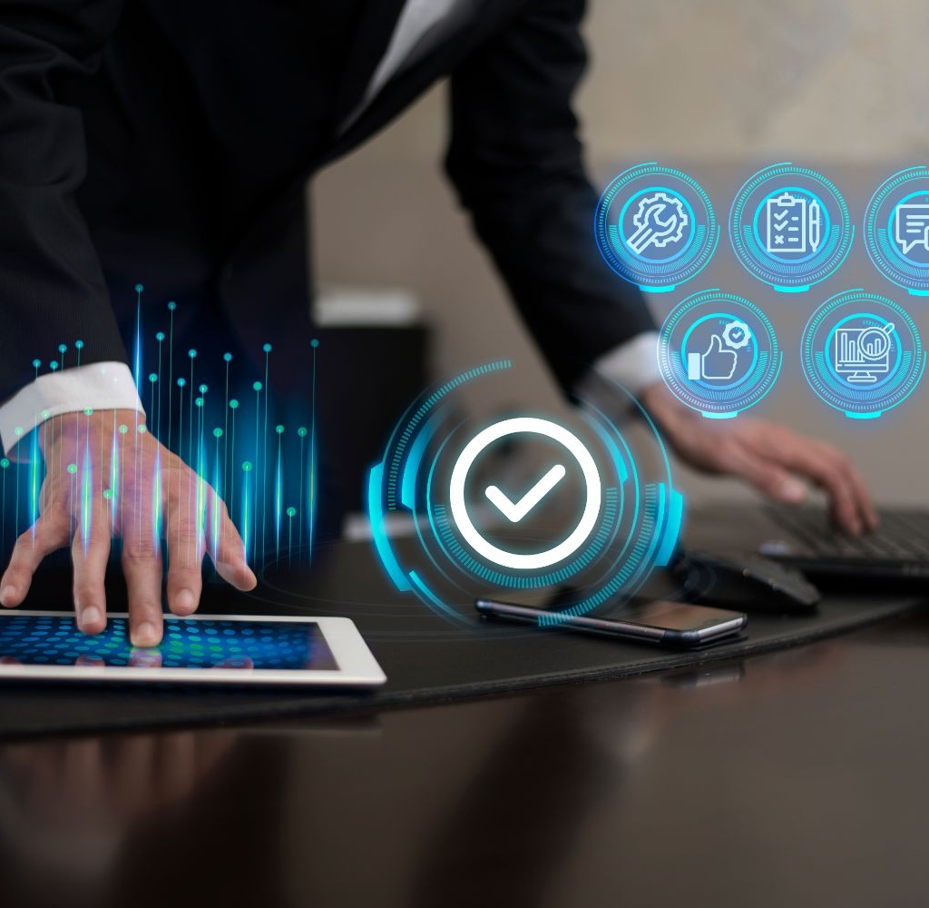 A person in a suit leans over a tablet on a desk, with a holographic checkmark icon above their hand, indicating the completion of annual compliance for a public limited company. Nearby are a laptop, smartphone, and holographic icons representing various digital functions including communication, checklist, and security.