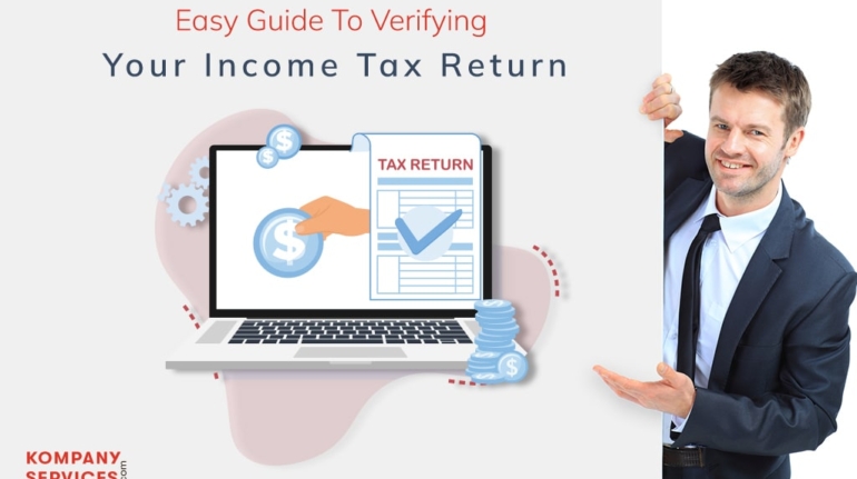 A man in a suit stands next to a poster featuring a laptop displaying a hand with a coin, and an income tax return document. The text reads, “Easy Guide To Verifying Your Income Tax Return.” The company name, "Kompany Services," is in the bottom left corner.